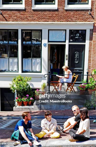 international group of friends talking by the canals of amsterdam - grachtenpand stock pictures, royalty-free photos & images