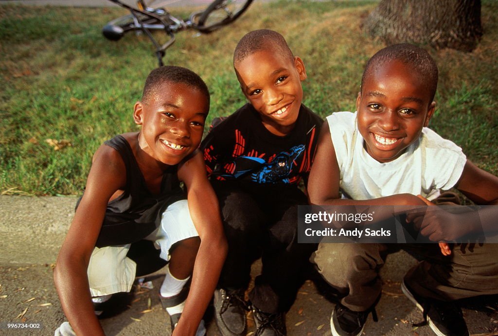 Three boys (5-7) sitting in group, smiling