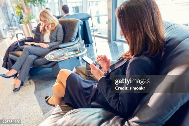 geschäftsfrauen auf stuhl am flughafen - technophiler mensch stock-fotos und bilder