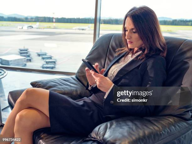 geschäftsfrau, die sitzen auf stuhl am flughafen - technophiler mensch stock-fotos und bilder