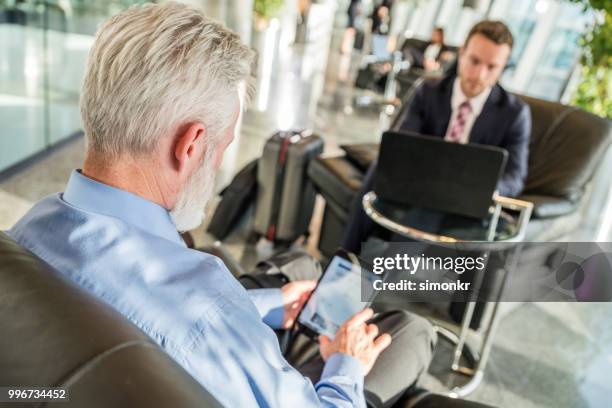 business-leute sitzen auf stuhl am flughafen - technophiler mensch stock-fotos und bilder