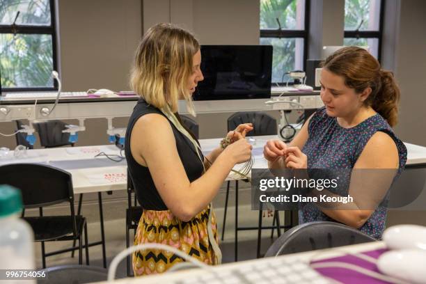 two female scientists standing in a laboratory discussing the details and usage of an eeg cable for neuroscience with a view of the laboratory in the background - the details imagens e fotografias de stock