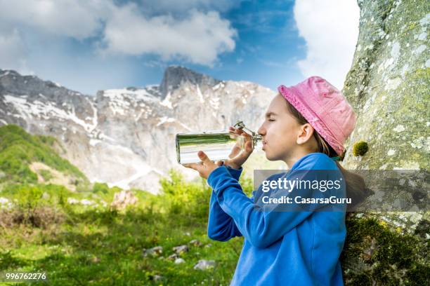 flicka avkopplande mot träd på mountain meadow dricksvattnet från flaska - casarsa bildbanksfoton och bilder