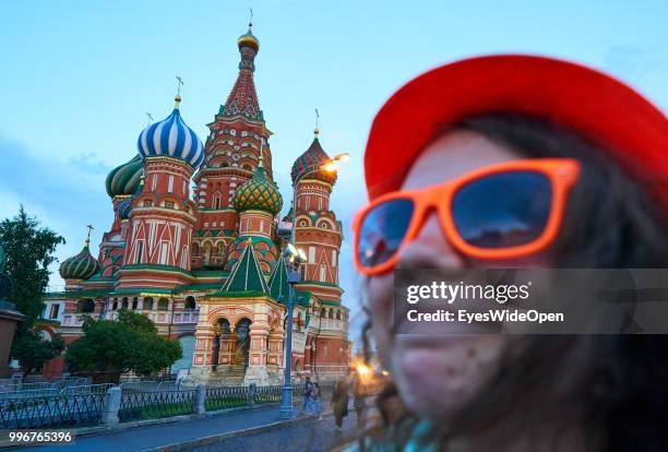 Young woman with orange hat and sunglasses poses on Red Square with Kremlin, Saint Basil's Cathedral , State Historical Museum on July 8, 2018 in...