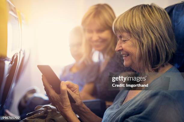 multi generation family travelling by plane - mother happy reading tablet stock pictures, royalty-free photos & images
