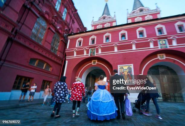 Russian couple in elegant dress walks through a gate at State Historical Museum on July 8, 2018 in Moscow, Russia.