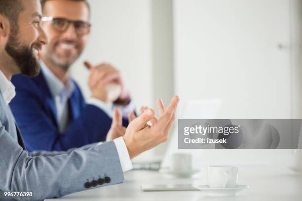 gelukkig zakenpartners tijdens vergadering - izusek stockfoto's en -beelden