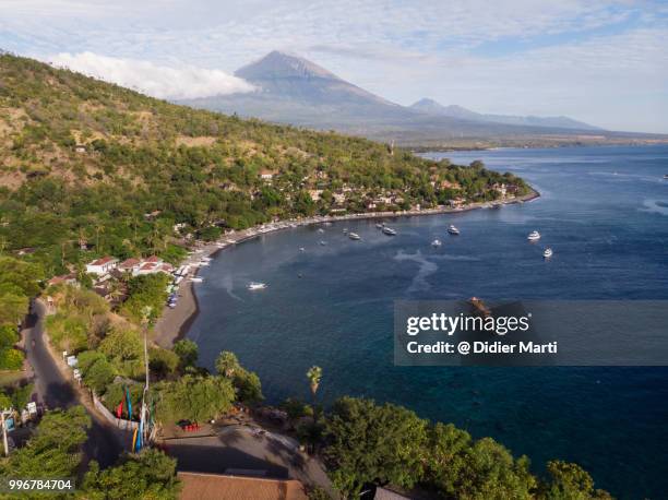 dramatic aerial view of the amed bay and beach with the agung volcano in the background in north bali on a sunny day - didier marti stock pictures, royalty-free photos & images
