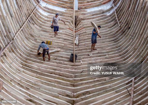 This picture taken on July 7, 2018 shows shipbuilders working on a traditional Pinisi boat in Tana Beru, on Indonesia's South Sulawesi island. - The...