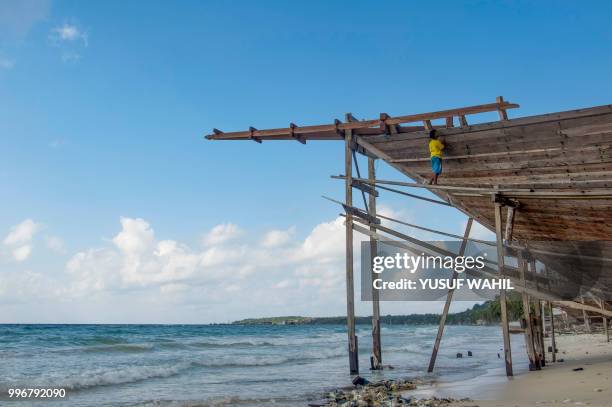 This picture taken on July 8, 2018 shows a shipbuilder working on a traditional Pinisi boat in Tana Beru, on Indonesia's South Sulawesi island. - The...