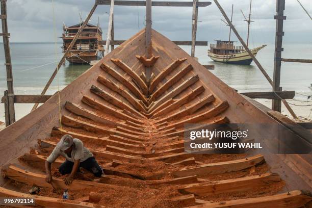 This picture taken on July 7, 2018 shows a shipbuilder working on a traditional Pinisi boat in Tana Beru, on Indonesia's South Sulawesi island. - The...