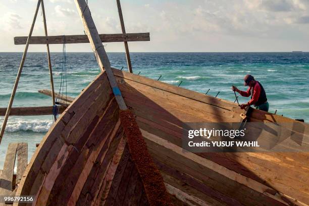 This picture taken on July 8, 2018 shows a shipbuilder working on a traditional Pinisi boat in Tana Beru, on Indonesia's South Sulawesi island. - The...