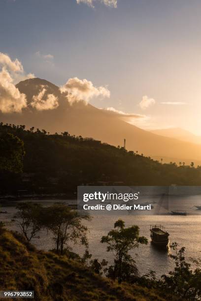 stunning sunset over the amed beach and bay with mt agung volcano in the background in bali in indonesia - didier marti stock pictures, royalty-free photos & images