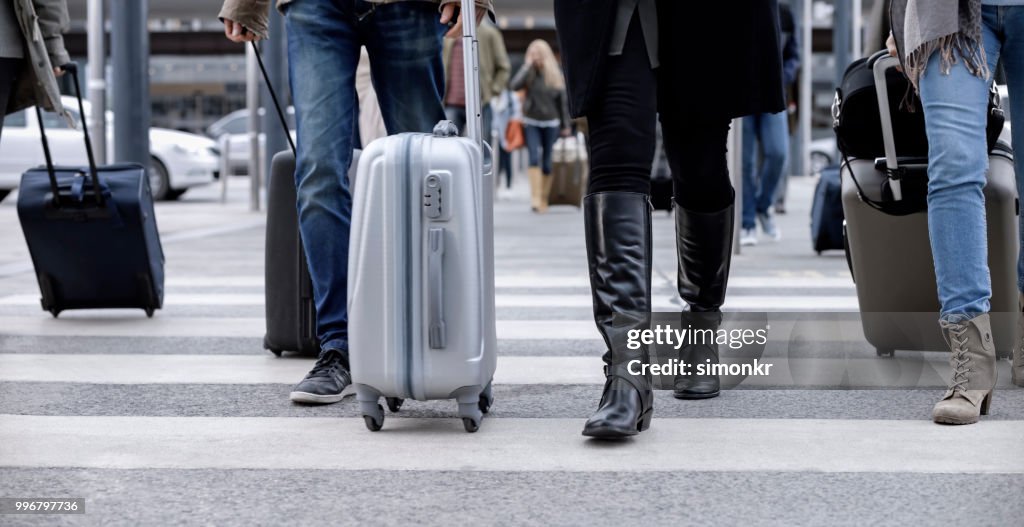 Business people walking with wheeled luggage