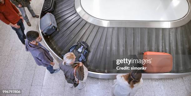 mensen uit het bedrijfsleven permanent bij bagage claim - airport slovenia stockfoto's en -beelden