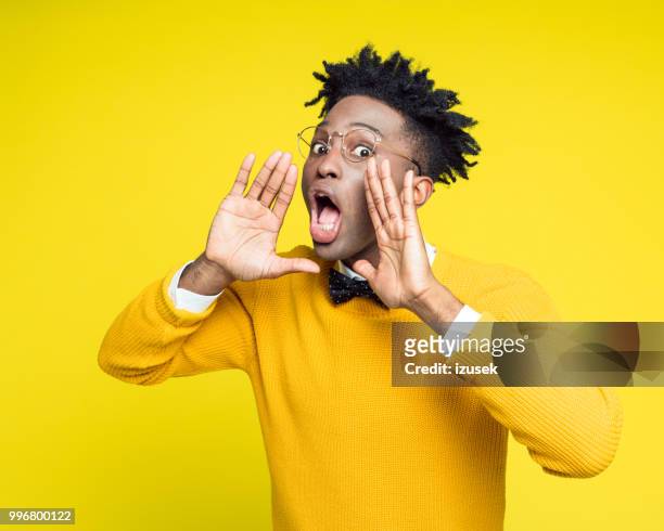 portrait of nerdy young man shouting against yellow background - izusek stock pictures, royalty-free photos & images