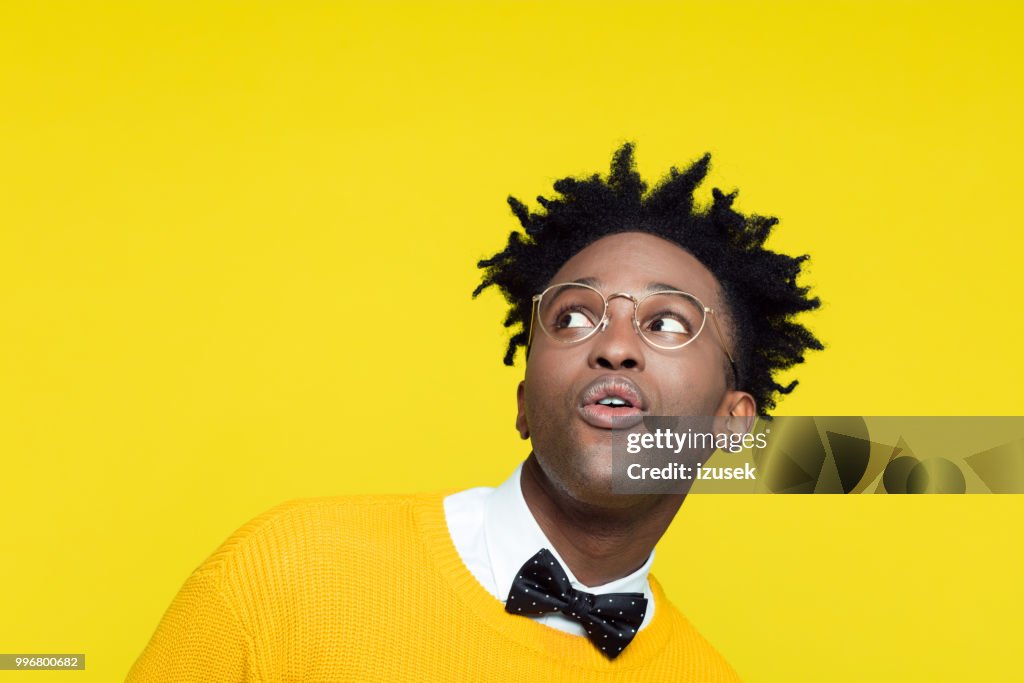 Funny portrait of surprised nerdy young man looking up