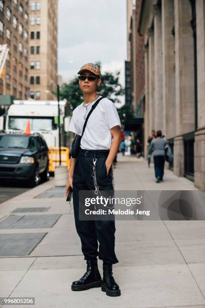 Model Fuji Ng in a Burberry check cap, white t-shirt, black pants, chain on the waist, and black combat boots during New York Fashion Week Mens...