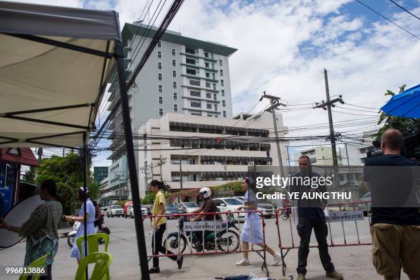 Members of media report across the street from the hospital where 12 boys and their coach rescued from a Thai cave recover in quarantine, in Chiang...