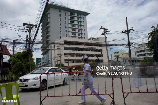 Nurse walks along the road across the street from the hospital where 12 boys and their coach rescued from a Thai cave recover in quarantine, in...