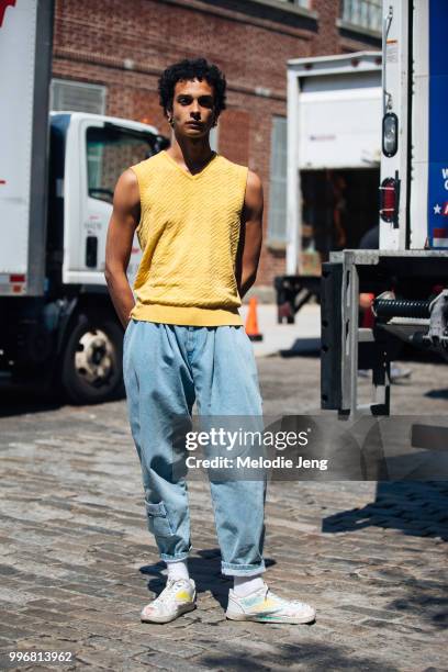 Amauri Pena in a yellow sleeveless top, light blue loose jeans, white sneakers with illustrations during New York Fashion Week Mens Spring/Summer...