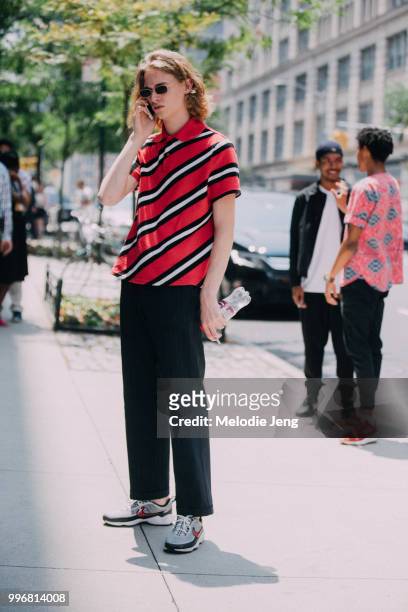 Model Simon Fakkert wears a diagonally red striped polo shirt, black pants, Nike sneakers, and talks on the phone uring New York Fashion Week Mens...