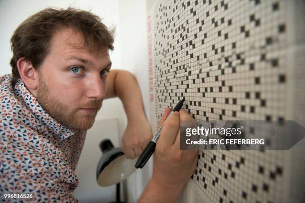 Crosswords maker at French daily newspaper Liberation Gaetan Goron poses in front of one of his giant crosswords in his office on July 10, 2018 in...