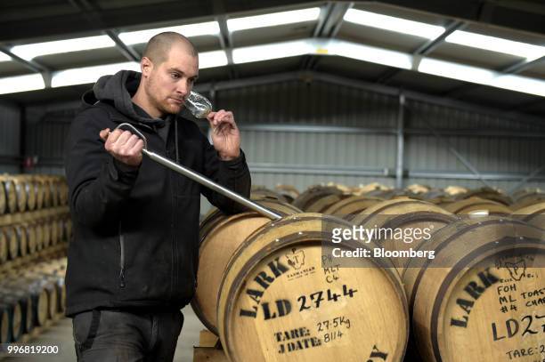 An employee smells a sample glass of Lark Whisky from a cask for tasting at the Lark Distillery Ltd. Whisky and gin distillery in Cambridge,...