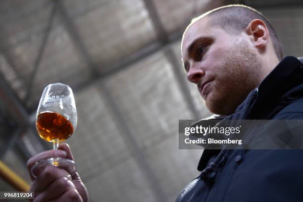 An employee holds a sample glass of Lark Whisky prior to tasting at the Lark Distillery Ltd. Whisky and gin distillery in Cambridge, Tasmania,...