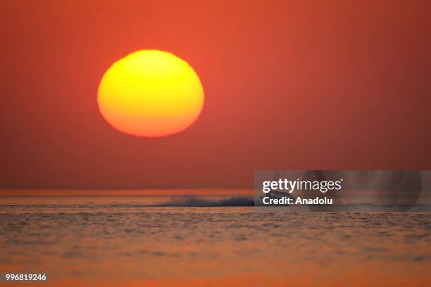 Man rides a jet ski through coastal side during a sunset at the second public beach of Lake Van, in Van, Turkey on July 12, 2018.