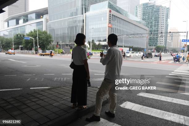 Couple waits to cross a road in Beijing's central business district on July 12, 2018.