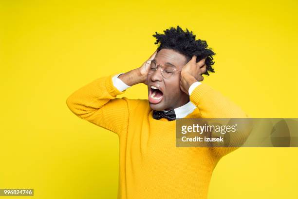 portrait of distraught geeky young man, yellow background - izusek stock pictures, royalty-free photos & images