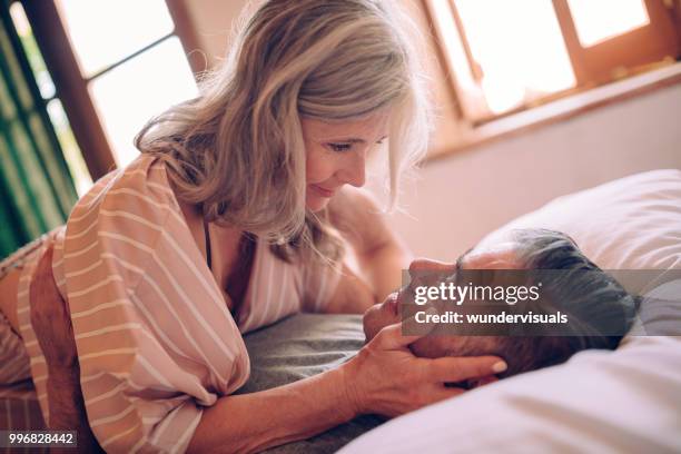 passionate mature couple flirting while lying down in bed - passion love stock pictures, royalty-free photos & images