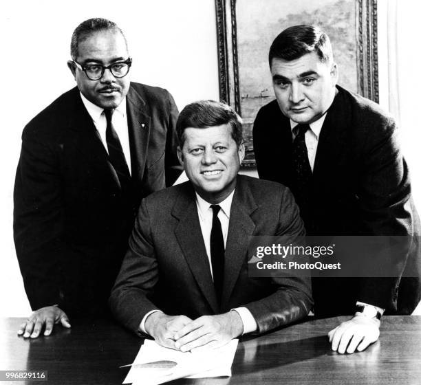 Portrait of American politician US President John F Kennedy as he poses with his recently appointed White House Press aides, Andrew Hatcher and...