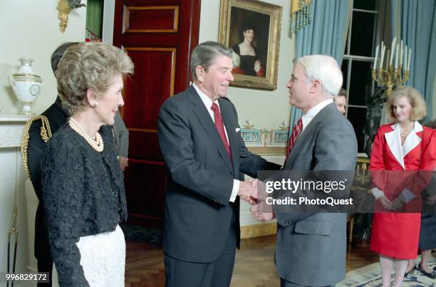 American politician US President Ronald Reagan shakes hands with Senator John McCain during a dinner for newly elected members of the 100th Congress,...