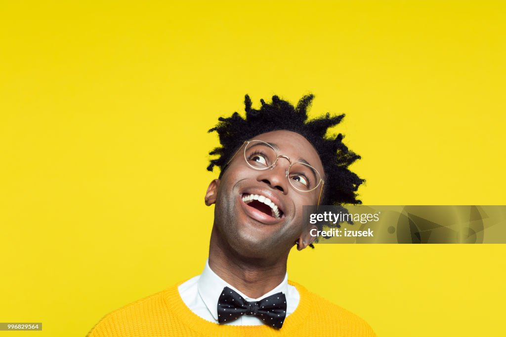 Funny portrait of excited nerdy young man looking up