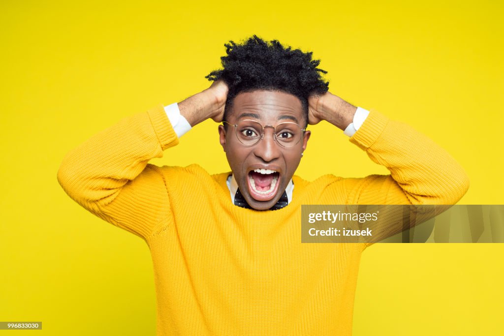 Portrait of frustrated geeky young man holding hands in hair