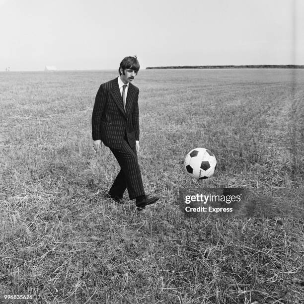 Ringo Starr, drummer with the Beatles, pictured kicking a football during filming of 'Magical Mystery Tour' in a field near Newquay in Cornwall on...