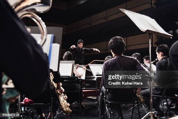orchestra playing musical instruments at concert hall - concierto de música clásica fotografías e imágenes de stock