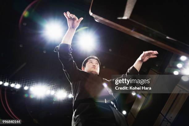 man conducting an orchestra at concert hall - orchestra conductor foto e immagini stock