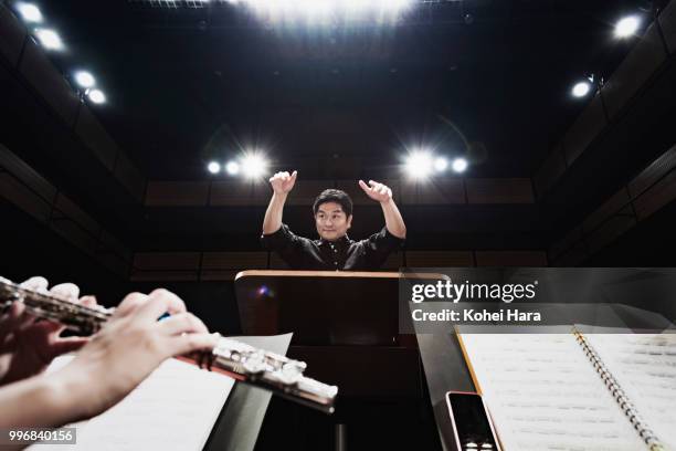 man conducting an orchestra at concert hall - orchestra stock pictures, royalty-free photos & images