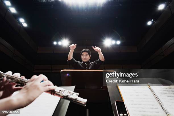 man conducting an orchestra at concert hall - music conductor stock pictures, royalty-free photos & images