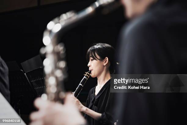 woman playing a clarinet at concert hall - klassieke orkestmuziek stockfoto's en -beelden