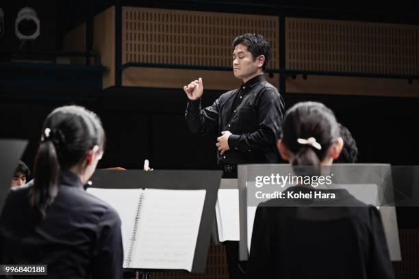 man conducting an orchestra at concert hall - classical orchestral music stock pictures, royalty-free photos & images