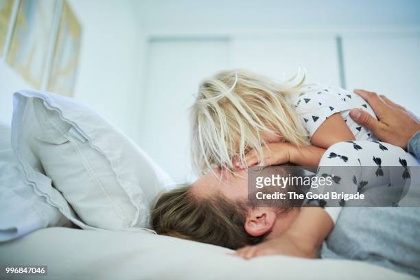 father playing with daughter on bed - zärtlich stock-fotos und bilder