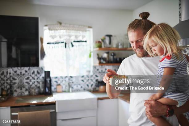 father carrying daughter while holding bowl of cereals in kitchen - sherman oaks bildbanksfoton och bilder