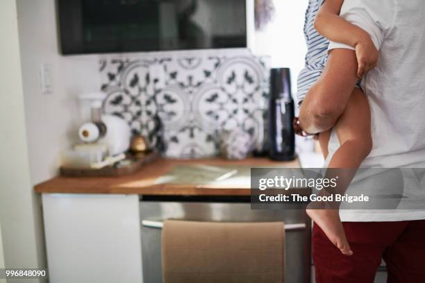 mid adult father carrying daughter in kitchen at home - sherman oaks fotografías e imágenes de stock