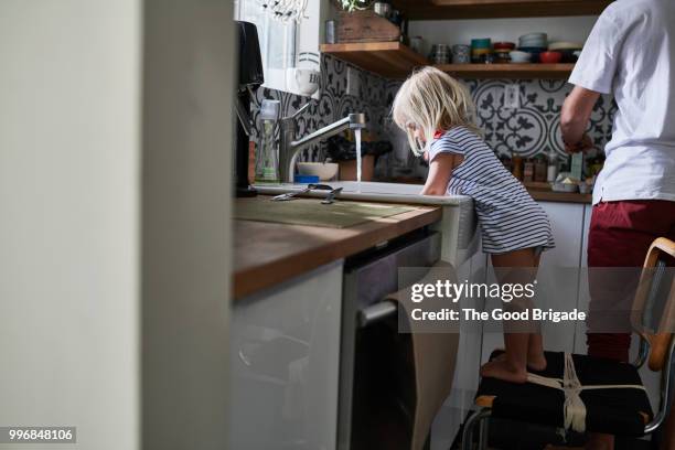 girl washing dishes at kitchen sink while father cooks breakfast - washing dishes stock pictures, royalty-free photos & images