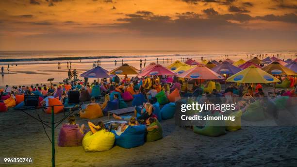 crowded beach at dusk in bali, indonesia - denpasar stock pictures, royalty-free photos & images