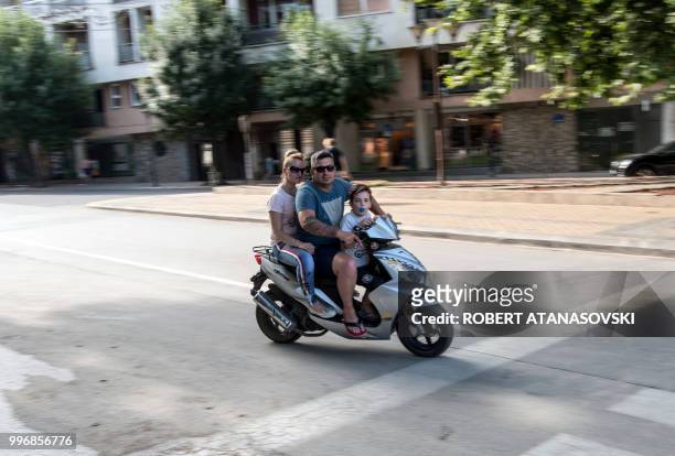 Members of a family ride a motorcycle in the city of Veles on June 12, 2018.